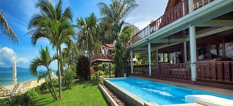 Beach side villa with swimming pool and palm trees.
