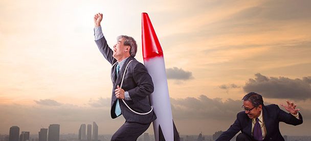 Two businessmen with a rocket on a Bangkok rooftop.