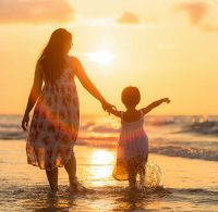 Mère et fille sur la plage avec coucher de soleil.
