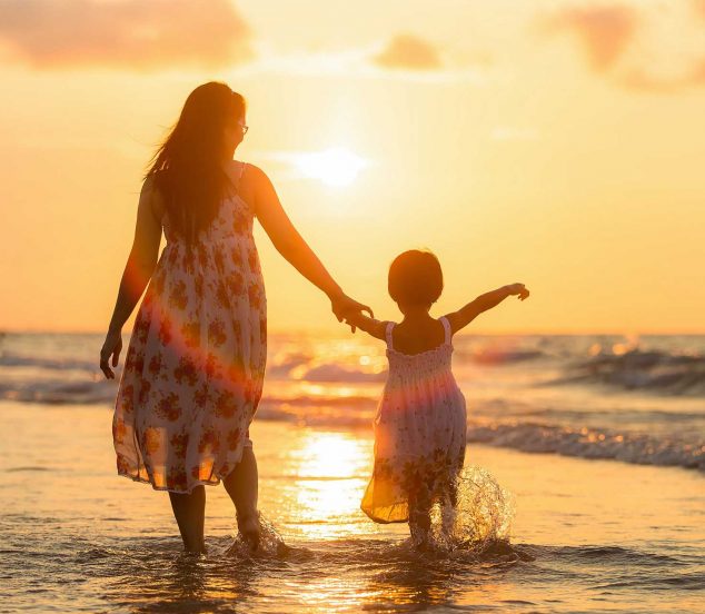 Mère et fille sur la plage avec coucher de soleil.