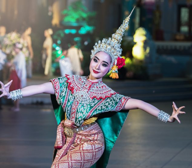 Woman in traditional Thai costume performing traditional Thai dance.