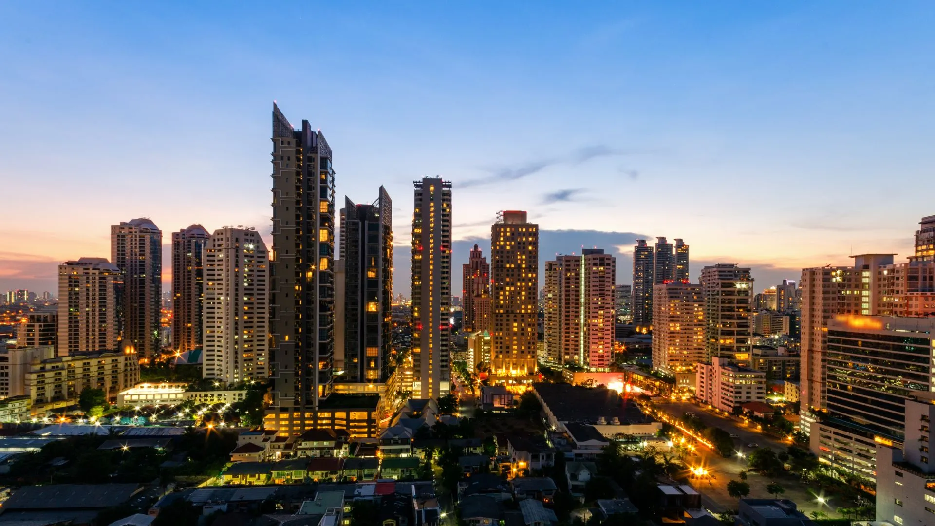 A beautiful view of Bangkok’s skyline at dusk, showcasing illuminated high-rise buildings and city lights.