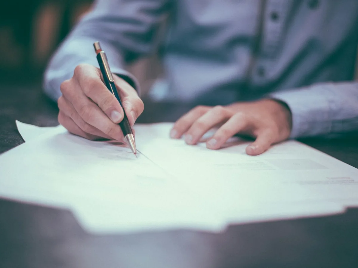 Close view of hands signing a property contract with a pen